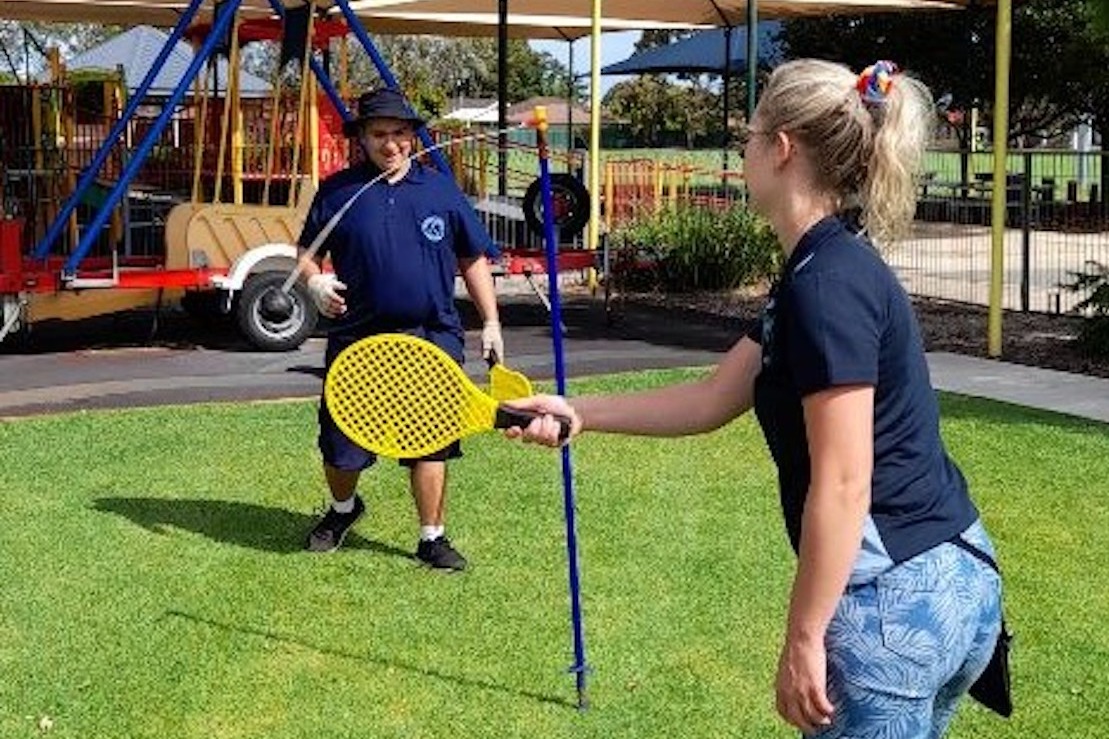 Image description: A male student who is Deaf plays totem tennis with a Student Support Officer (SSO).